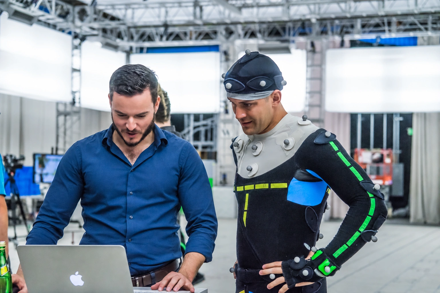 A director reviewing a laptop with a motion-capture performer